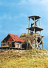 Gun tower with corrugated iron roof building and thatched roof building in background 