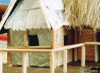 Close up of unpainted hooch with corrugated iron and thatched roof and showing foil "woven" wall coverings